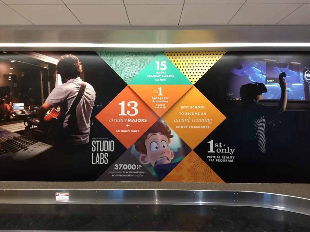 Wall mural features film and animation stats, students using studio equipment, and graphics highlighting awards, creative majors, and virtual reality programs at a college.