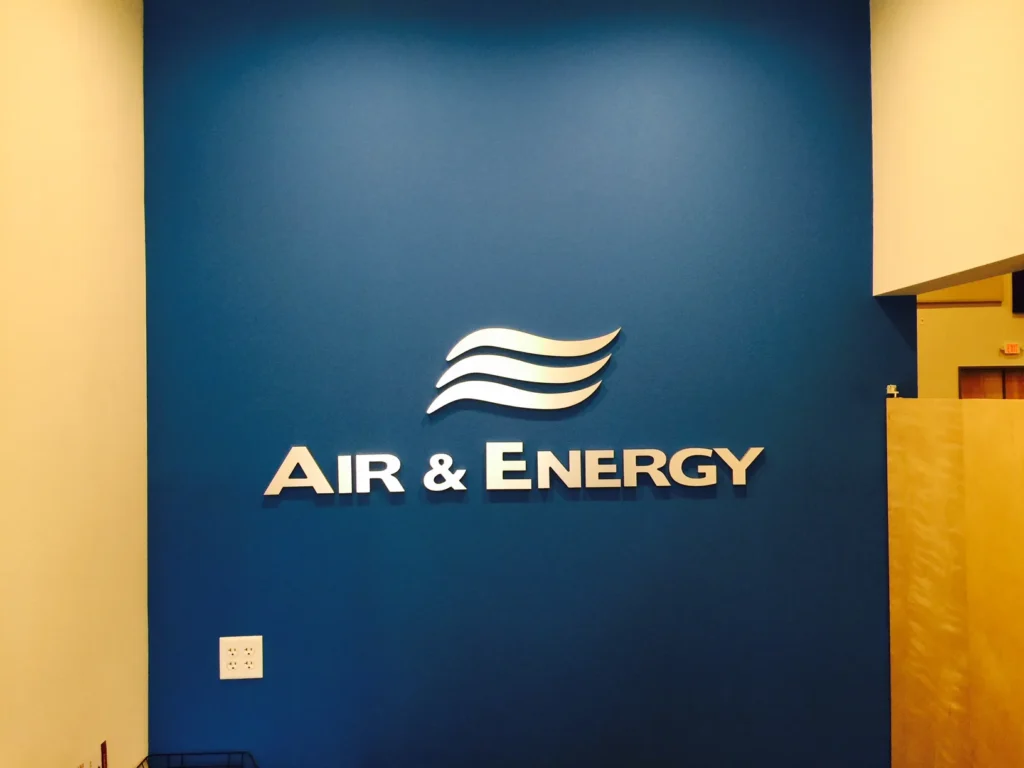 Logo for “Air & Energy” on a blue wall, featuring three white wave-like lines above the company name in silver letters.