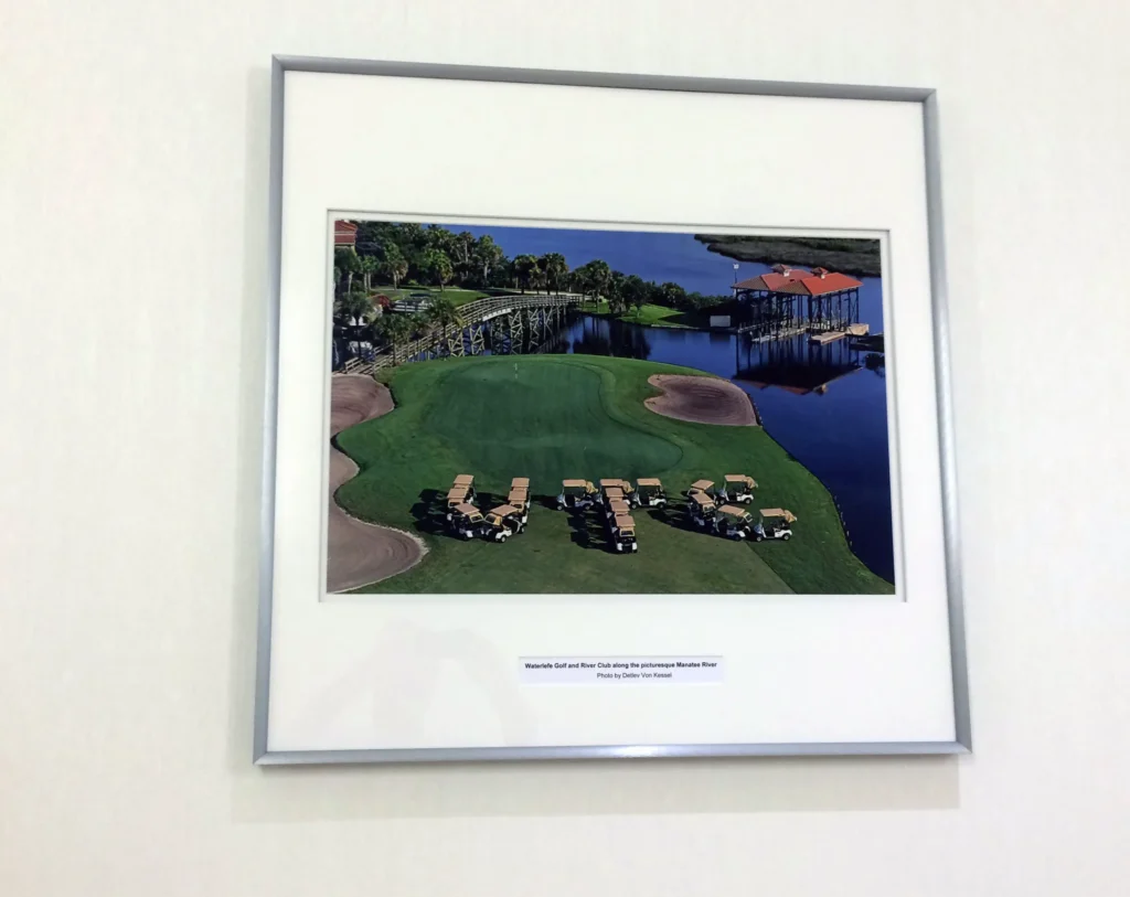 A framed photo shows golf carts arranged on a golf course spelling out “UTC” near a bridge and water.