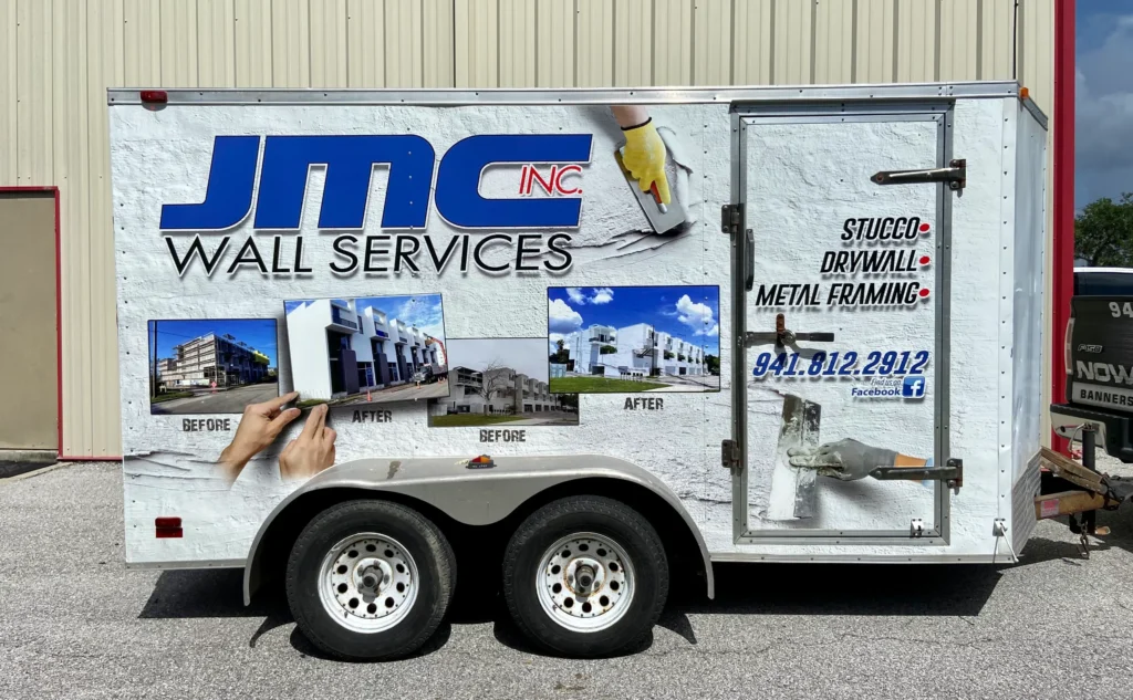 White trailer advertising “JMC Wall Services” with before-and-after building photos, contact info, and listed services: stucco, drywall, metal framing.