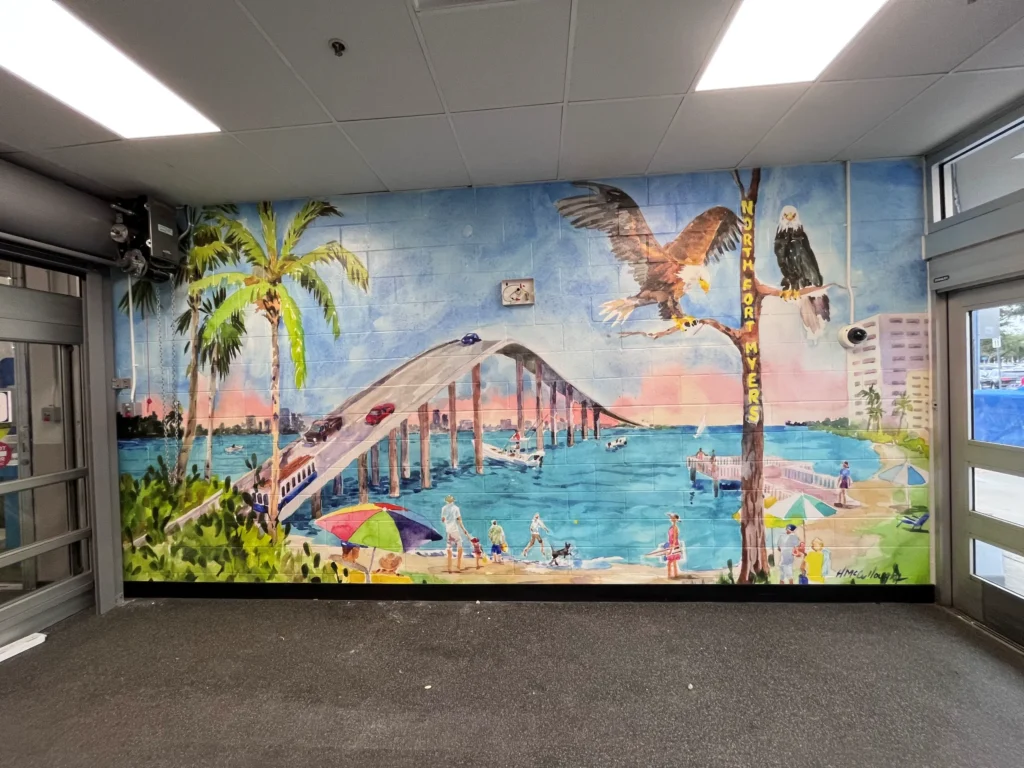 Mural of a beach scene with a bridge, palm trees, people, umbrellas, boats, and two bald eagles, with “Fort Myers” written vertically on the right side.