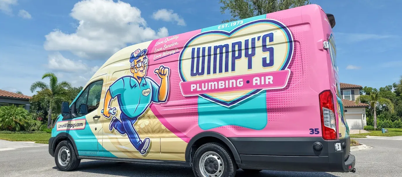 A pink and turquoise Wimpy’s Plumbing & Air work van featuring a cartoon plumber and the company logo.